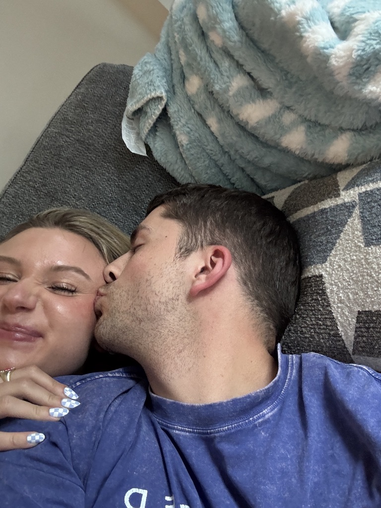 Kenny kissing Macie on the cheek on the couch