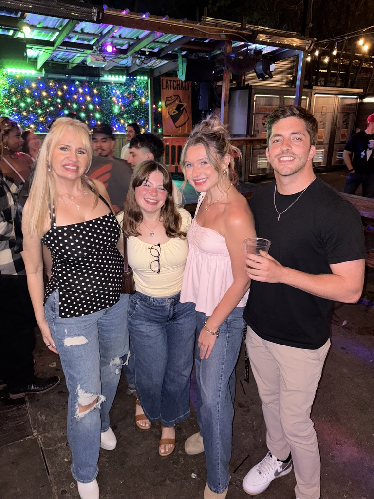 Macie, Kenny and family at a bar with string lights