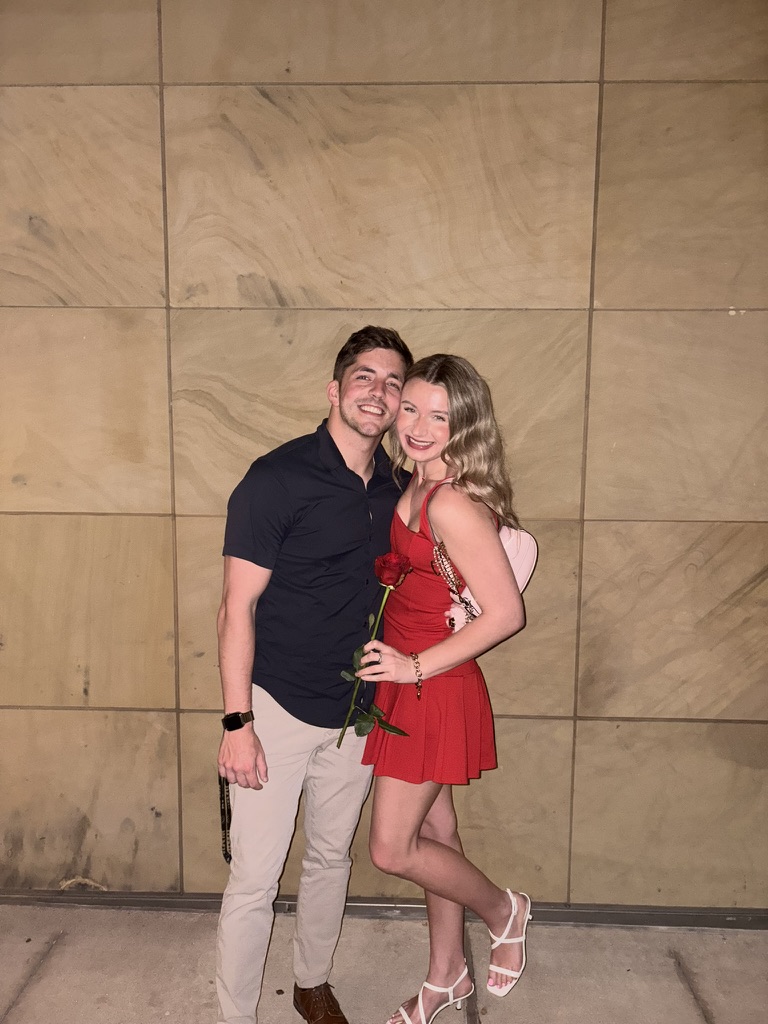 Macie in a red dress holding a rose next to Kenny