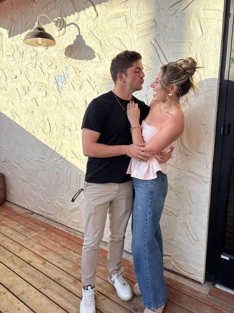 Kenny kissing Macie against a white wall in golden light